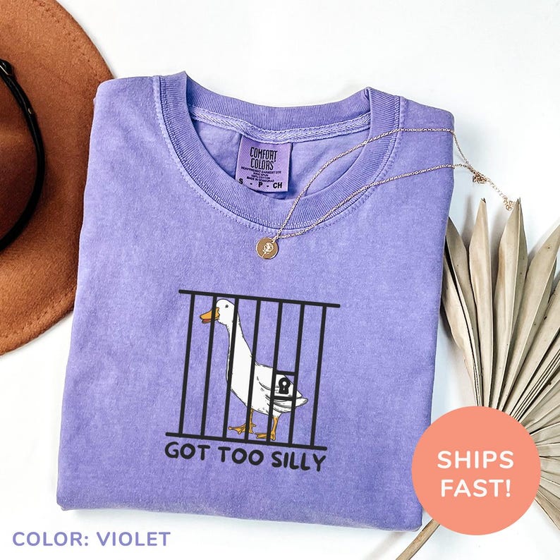 a purple shirt with a picture of a duck in a cage