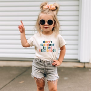 a little girl wearing sunglasses and a happy birthday t - shirt