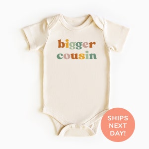 a white baby bodysuit with the words bigger cousin printed on it