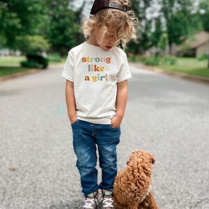 a little boy standing next to a brown dog