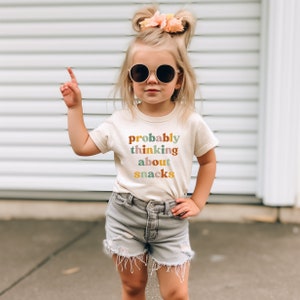 a little girl wearing a t - shirt that says probably thinking about chalk