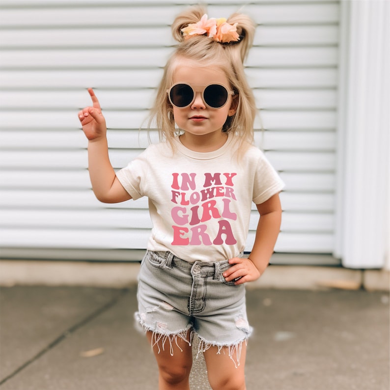 a little girl wearing a t - shirt that says i'm my flower girl