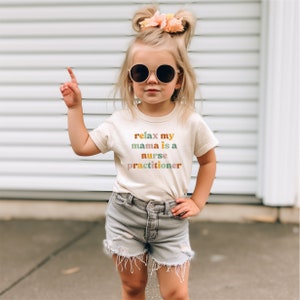 a little girl wearing a t - shirt that says play my mama is a nurse