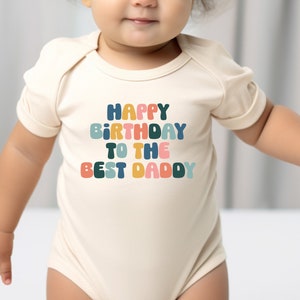 a baby wearing a bodysuit that says happy birthday to the best daddy