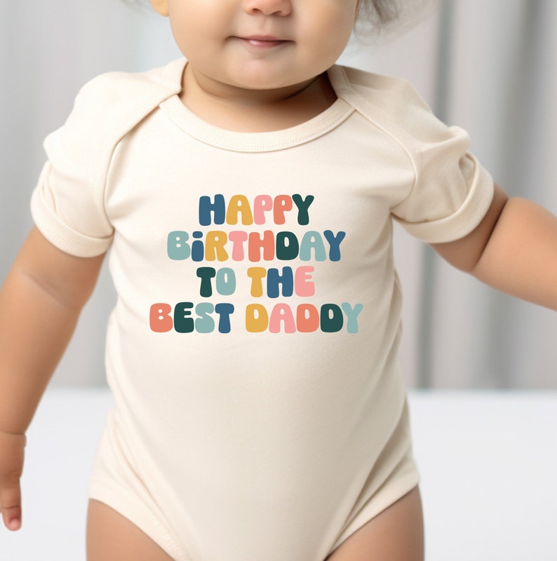 a baby wearing a bodysuit that says happy birthday to the best daddy