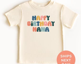 May include: Cream-colored t-shirt with the text "HAPPY BIRTHDAY NANA" in colorful, rounded letters. The shirt is a short-sleeved crew neck style, perfect for a birthday celebration. The design is centered on the front of the shirt.