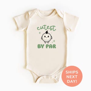 A white baby onesie with a cute cartoon character and the text "cutest by par" printed on it.