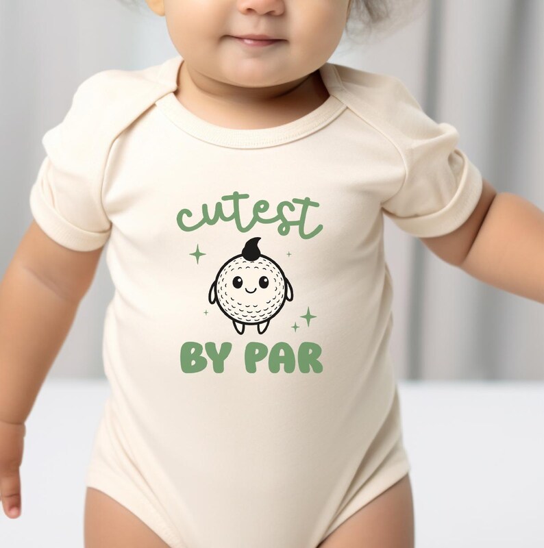 A baby wearing a white onesie with a cartoon character and text printed on it.