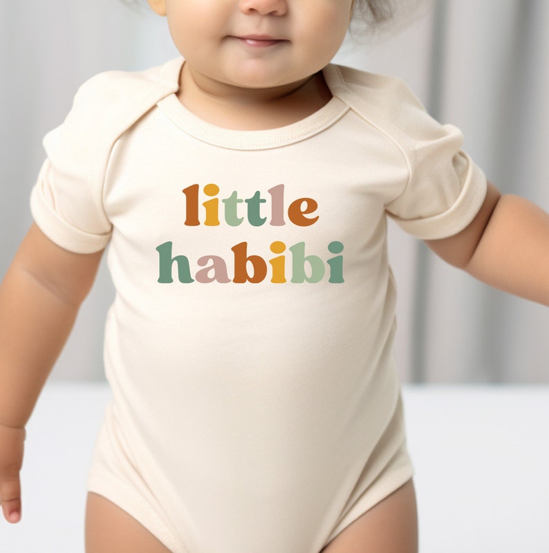 a baby wearing a bodysuit that says little habii