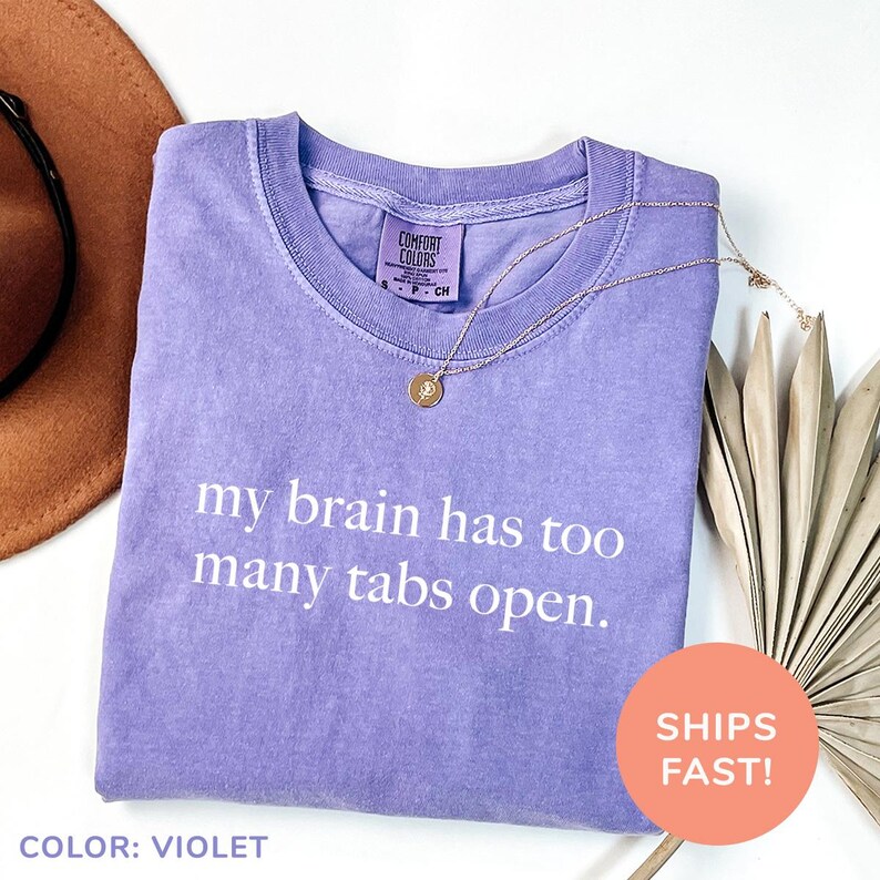 a purple shirt that says, my brain has too many tabs open