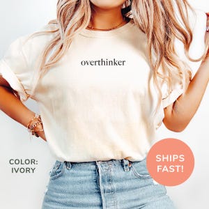 a woman wearing a white shirt with the words overthiker on it