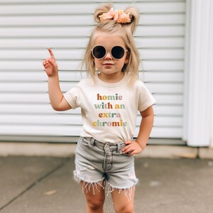 a little girl wearing sunglasses and a t - shirt that says home with an extra