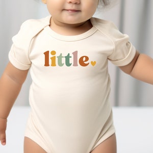 a baby wearing a bodysuit with the word little on it