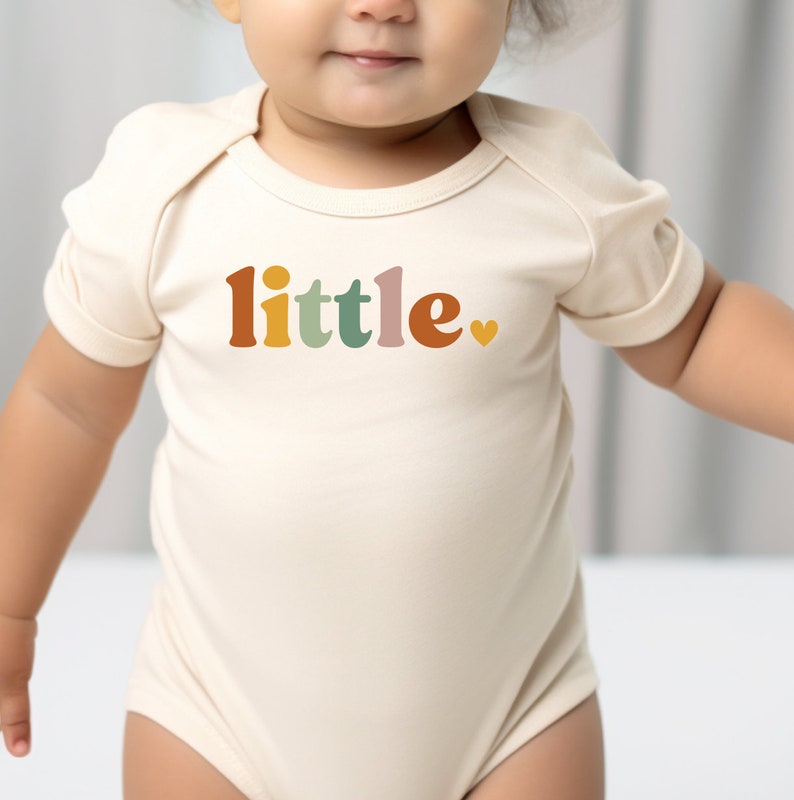 a baby wearing a bodysuit with the word little on it