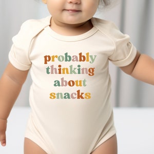 a baby wearing a bodysuit that says probably thinking about snacks