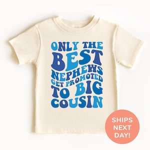 May include: Cream-colored toddler t-shirt with the text "ONLY THE BEST NEPHEWS GET PROMOTED TO BIG COUSIN" in shades of blue. The shirt has short sleeves and a round neckline. A peach-colored circle with the text "SHIPS NEXT DAY!" is in the lower right corner.