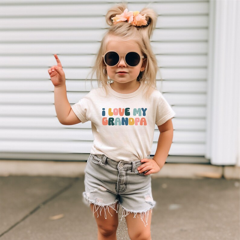 a little girl wearing a t - shirt that says i love my grandpa