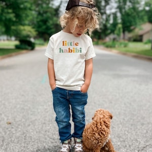 a little boy standing next to a brown dog