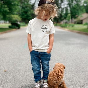 a little boy standing next to a brown dog