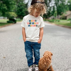 a little boy standing next to a brown dog