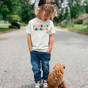 a little boy standing next to a brown dog