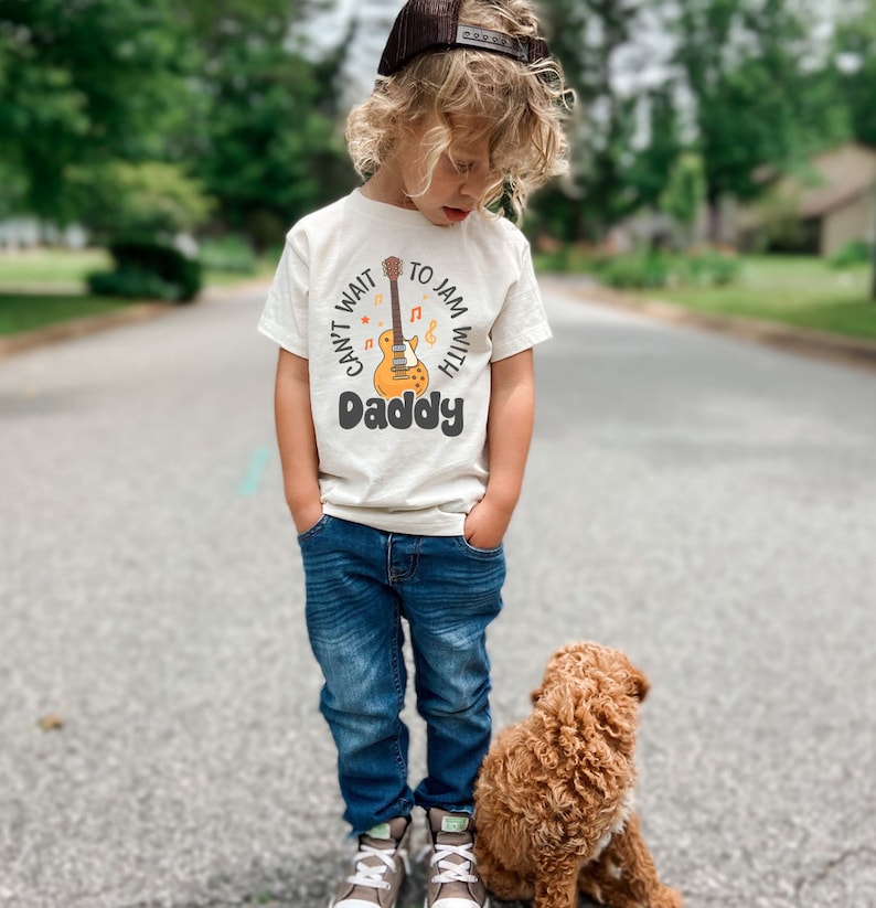 a little boy standing next to a brown dog