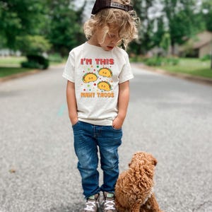 a little boy standing next to a brown dog