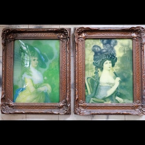 May include: Two framed vintage portraits of women. The portraits feature women in period clothing and hats, set against a green background. The frames are ornate, with a dark brown finish. The artwork evokes a sense of historical elegance.