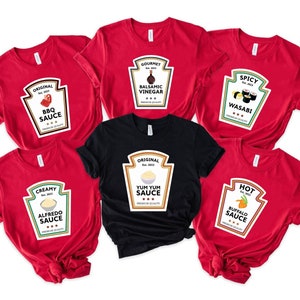 May include: A collection of red and black t-shirts featuring sauce-themed designs. Each shirt displays a label with a different sauce name, such as "BBQ Sauce," "Wasabi," and "Buffalo Sauce." The labels are in a classic bottle shape.