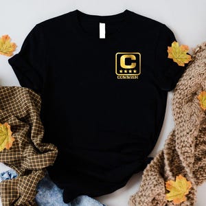 a black t - shirt with yellow and brown leaves on it