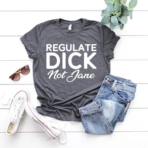 May include: A dark gray t-shirt with the text "Regulate Dick Not Jane" printed in white.