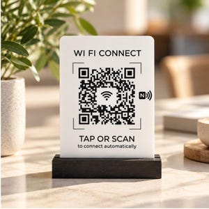 Könnte beinhalten: Ein rechteckiges weißes Schild mit einem schwarzen Holzsockel, das den Text WI FI CONNECT und TAP OR SCAN to connect automatically zeigt. Das Schild enthält einen großen schwarz-weißen QR-Code mit einem zentralen WLAN-Symbol und einem NFC-Symbol.