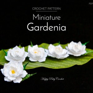 May include: Crochet pattern for a miniature white gardenia flower. The pattern is called "Miniature Gardenia" and is available as a PDF e-book. The image shows five crocheted gardenias on a green leaf.
