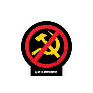 Może przedstawiać: Naklejka z czarnym tłem przedstawiająca żółty symbol młota i sierpa przekreślony czerwonym okręgiem i ukośnikiem. Tekst "@AntiKommunic" znajduje się na dole.