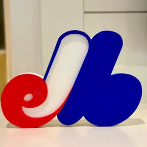Puede incluir: Un logotipo 3D del equipo de hockey de los Canadiens de Montreal. El logotipo está formado por tres partes: una "C" roja, una "J" blanca y una "A" azul.