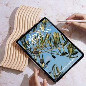 May include: A digital tablet displays the words "eternal HAPPINESS" over a blue sky and olive branch image. A wooden, wavy sculpture and a stylus are also in the image. The text "2026 CONVENTION OF JEHOVAH'S WITNESSES" is at the bottom of the screen.
