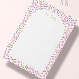 May include: White notepad with a floral border in shades of purple and gold. The notepad has lined paper and the word "notes" printed in gold at the top.