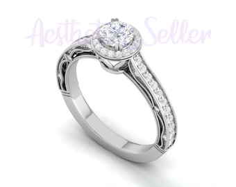 May include: A silver engagement ring with a round, clear center stone surrounded by a halo of smaller stones. The band is adorned with a delicate, intricate design and a row of smaller stones.