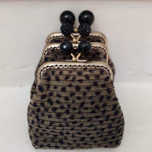 May include: A set of three small, brown, leopard print purses with gold metal frames and black bead accents.