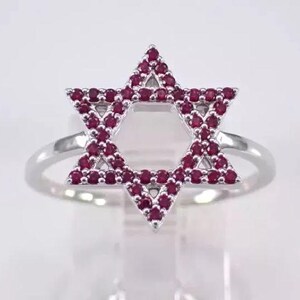 May include: A silver ring with a red ruby star of David design.