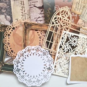 Op de afbeelding: Een verzameling scrapbook versieringen in vintage stijl. Inclusief sierlijke frames, papieren doilies, decoratieve uitsparingen en verouderde papieren ephemera in bruin, cr&egrave;me en groen. Ideaal voor knutsel- en journaling projecten.