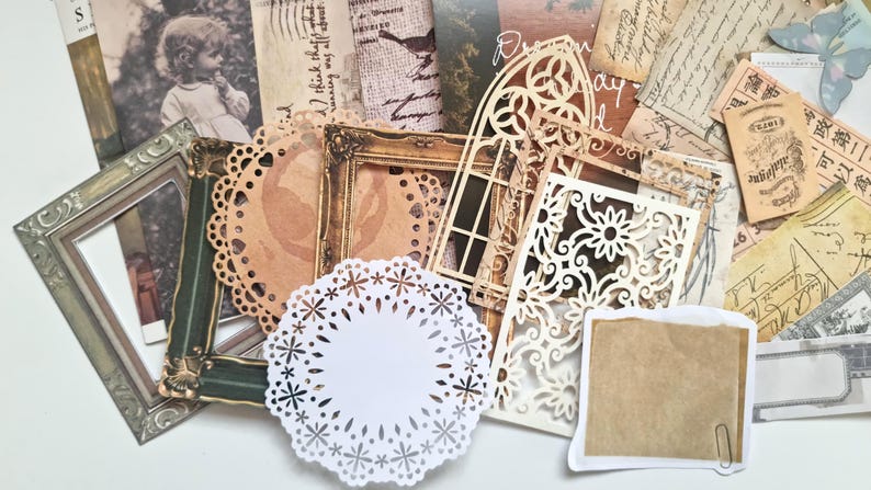 Op de afbeelding: Een verzameling scrapbook versieringen in vintage stijl. Inclusief sierlijke frames, papieren doilies, decoratieve uitsparingen en verouderde papieren ephemera in bruin, cr&egrave;me en groen. Ideaal voor knutsel- en journaling projecten.