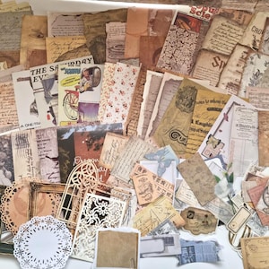 Op de afbeelding: Een verzameling papieren ephemera in vintage-stijl, waaronder verouderde papieren vellen, ansichtkaarten, labels en decoratieve elementen. De papieren hebben vervaagde kleuren, antieke lettertypen en illustraties, wat een nostalgische uitstraling cre&euml;ert.