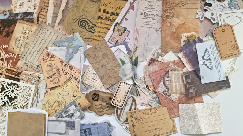 Op de afbeelding: Een verzameling vintage papieren ephemera, waaronder labels, ansichtkaarten en papieren met patronen. De papieren hebben verouderde texturen, vervaagde kleuren en handschrift, met vlinder- en bloemaccenten. Ideaal voor scrapbooking en knutselen.