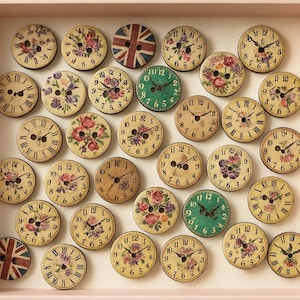 May include: A collection of decorative wooden buttons with clock faces and floral designs. Some buttons feature the Union Jack flag. The buttons are arranged in a pink rectangular box, creating a vintage aesthetic.
