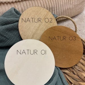 May include: Three round wooden discs with the text "NATUR 01", "NATUR 02", and "NATUR 03" printed on them. The discs are different shades of wood, from light to dark.