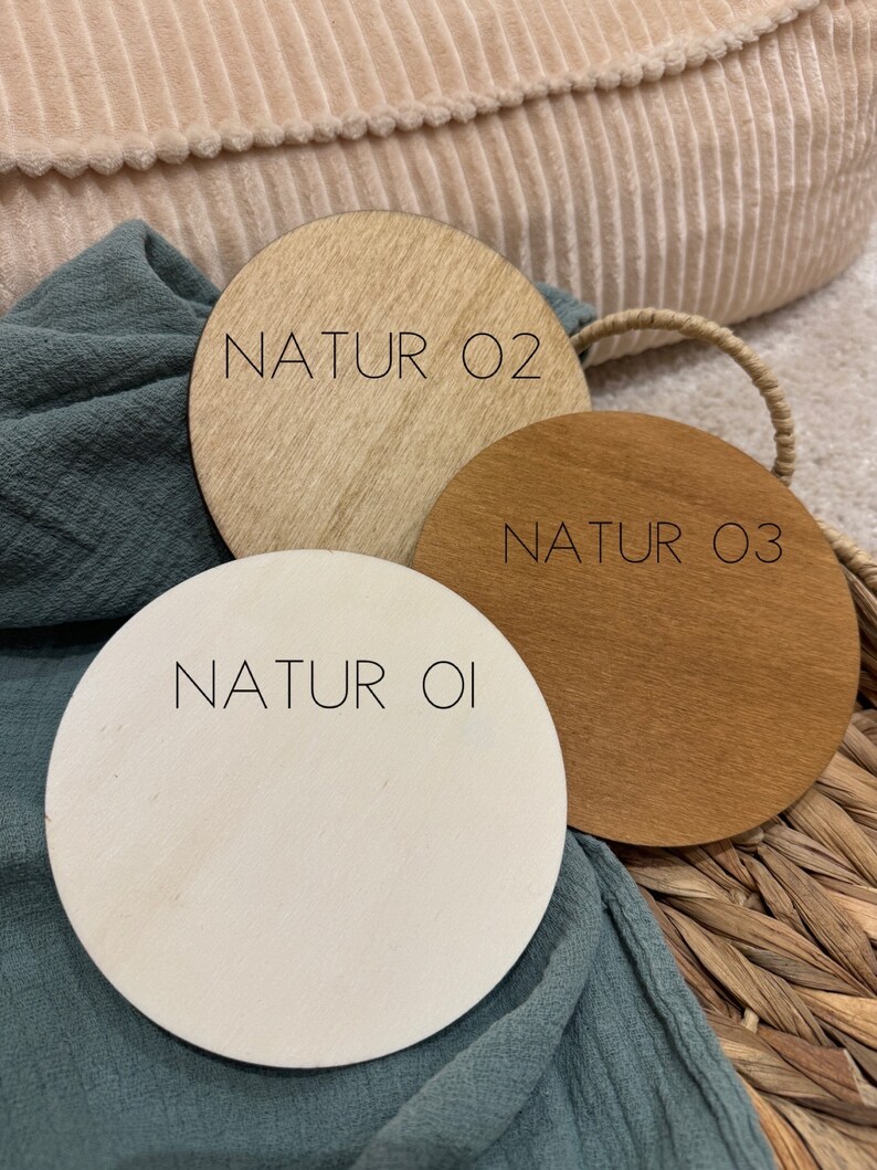 May include: Three round wooden discs with the text "NATUR 01", "NATUR 02", and "NATUR 03" printed on them. The discs are different shades of wood, from light to dark.