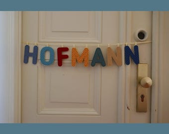 Łańcuszek z literami wykonany z materiału, zaprojektowany indywidualnie - na drzwi do mieszkania, przedpokój lub salon