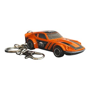 May include: An orange and black sports car keychain featuring the number 80 in a white circle on the side door. The die-cast metal vehicle has black racing stripes on the hood and roof, black wheels, and a silver metal split ring and lobster clasp.