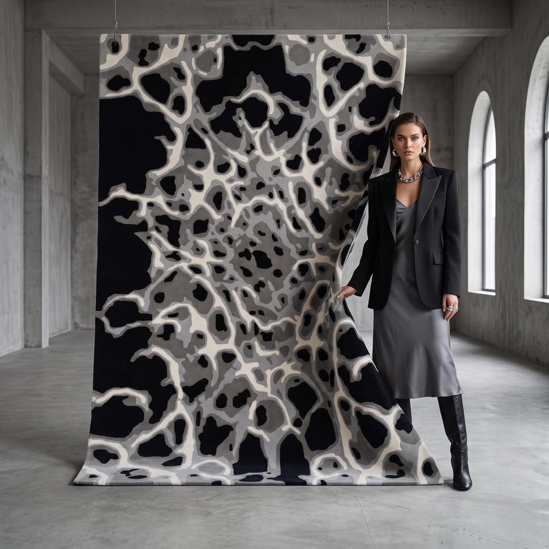 Puede incluir: Una alfombra rectangular grande con un patr&oacute;n org&aacute;nico abstracto en tonos negro, blanco y gris. El dise&ntilde;o consiste en formas fluidas interconectadas que se asemejan a un mapa celular o topogr&aacute;fico, exhibido en una orientaci&oacute;n vertical.